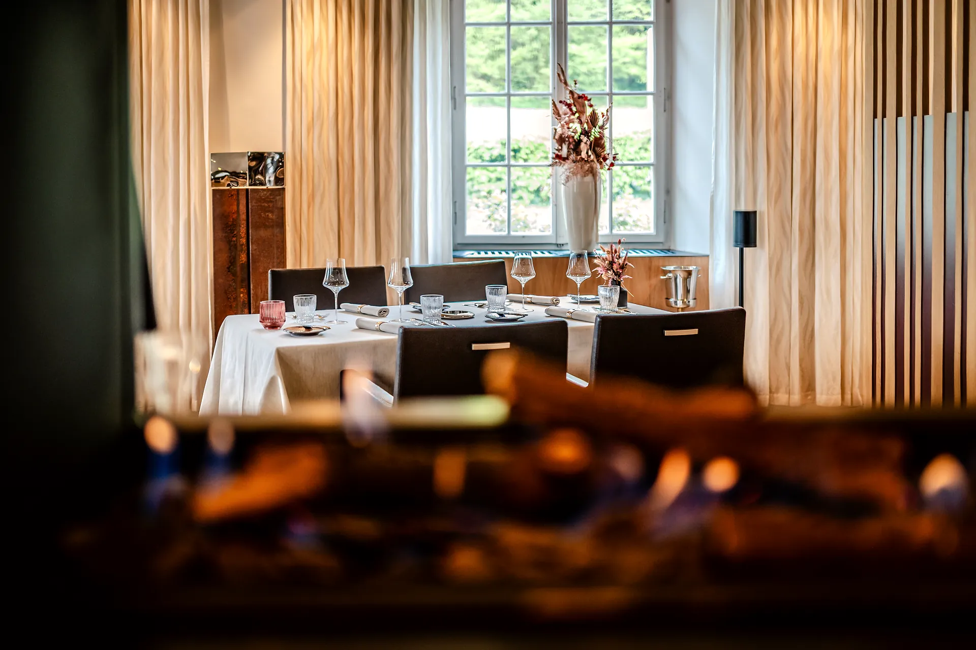 Gedeckter Tisch im Restaurant Le Feu mit offenem Feuer im Vordergrund