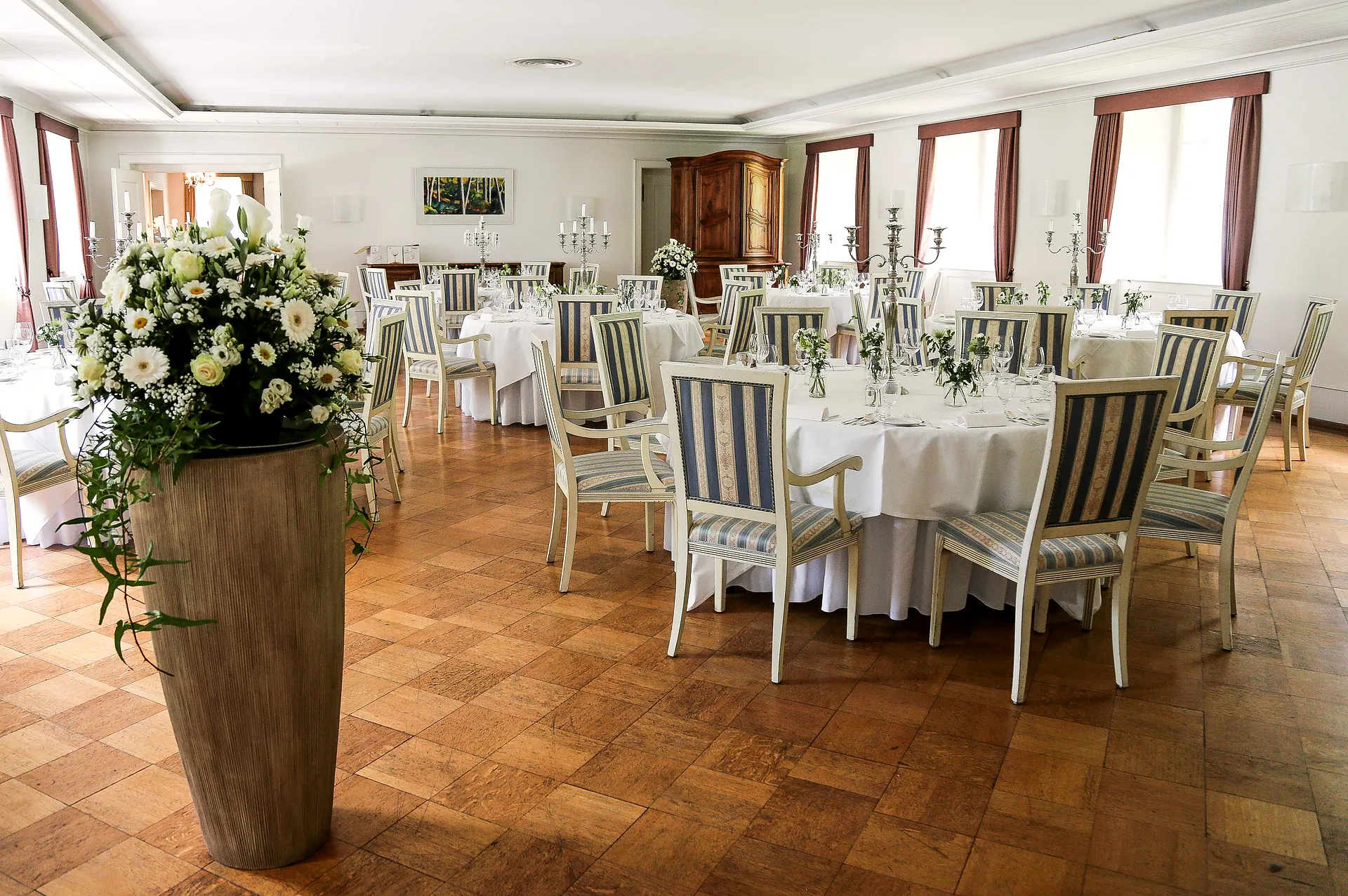 Heller Saal mit runden Tischen und Blumenschmuck